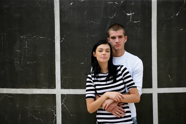 Young urban couple stood by wall — Stock Photo, Image