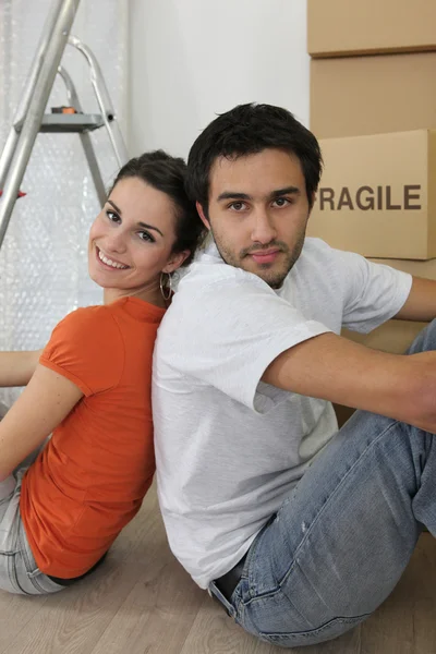 Couple sat by ladder and boxes — Stock Photo, Image
