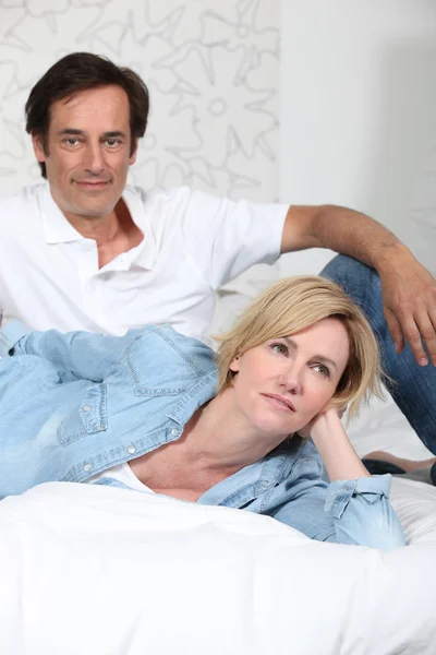 Completamente vestita coppia sdraiata su un letto a guardare la televisione — Foto Stock