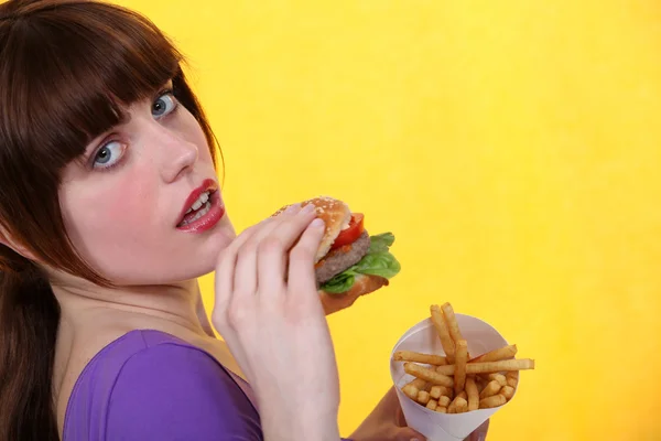 Žena jíst hamburger a hranolky — Stock fotografie