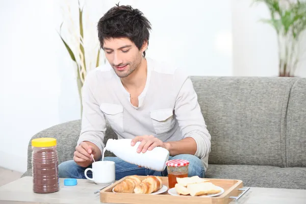 Ung man äter frukost i hans vardagsrum — Stockfoto
