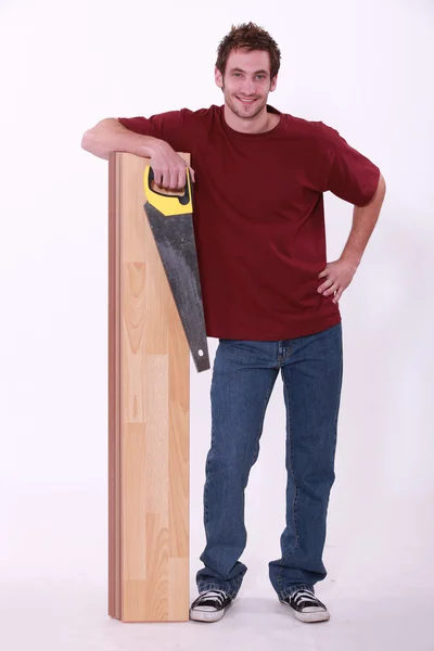 男人站与强化木地板和锯 — 图库照片