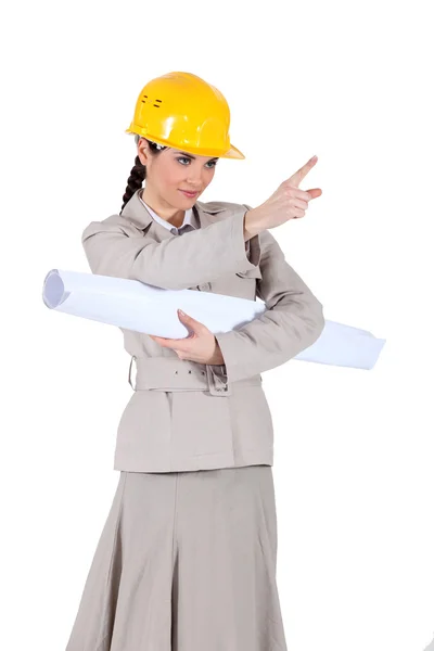 Businesswoman holding a blueprint and pointing at something — Stock Photo, Image