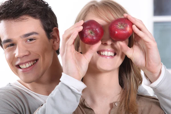 Junger Mann mit roten Äpfeln vor den Augen seiner Freundin — Stockfoto