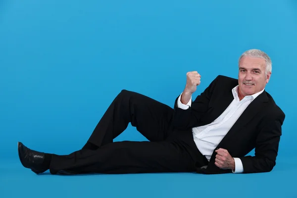A mature businessman laying on the floor gesturing a yes sign. — Stock Photo, Image