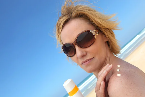 Woman at beach applying sun cream — Stock Photo, Image