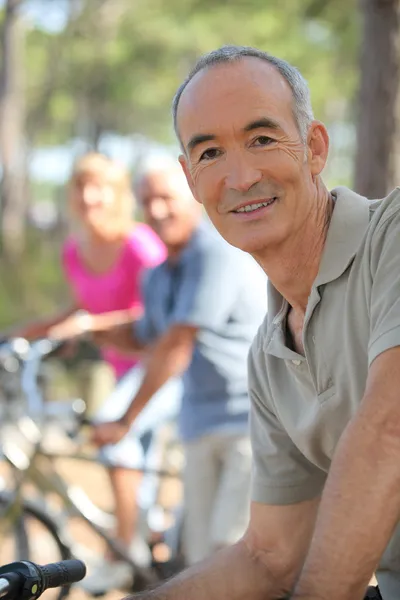 Homem mais velho andando de bicicleta na floresta com amigos — Fotografia de Stock