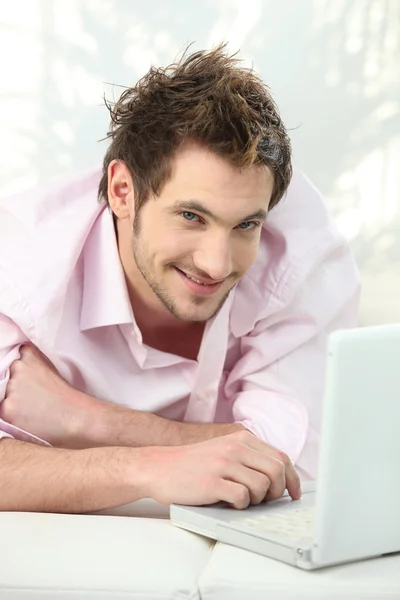 Young man lying on couch using laptop — Stock Photo, Image