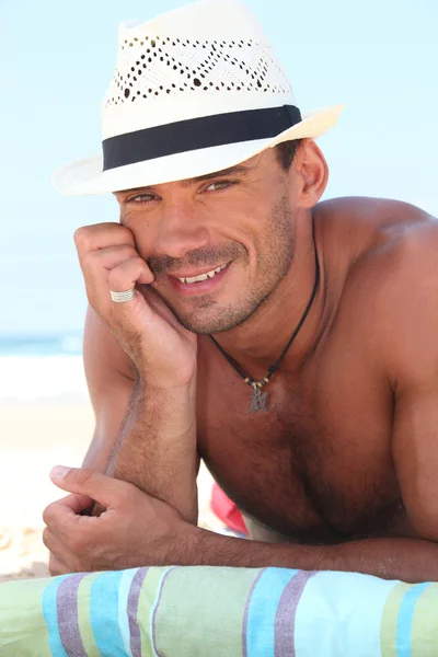 一顶草帽躺在海滩上的肌肉男人 — 图库照片