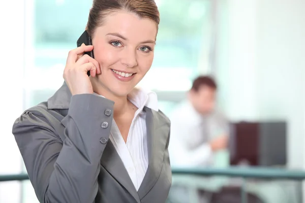Zakenvrouw met behulp van een mobiele telefoon in een kantoor — Stockfoto