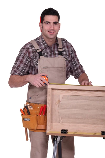Un carpintero trabajando en la puerta de un armario . —  Fotos de Stock