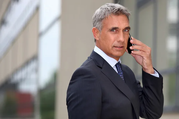 Homme d'affaires mature utilisant un téléphone portable à l'extérieur — Photo