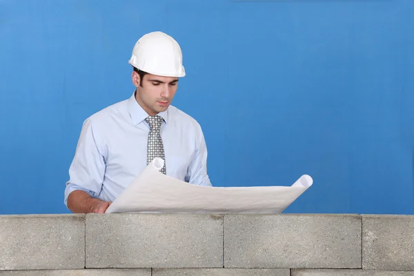 Ingeniero inspeccionando un plano de construcción — Foto de Stock