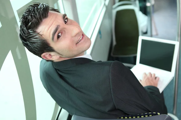 Hombre joven de cabello castaño en un autobús con computadora —  Fotos de Stock