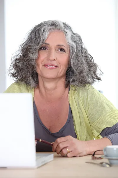 Γκρίζα μαλλιά γυναίκα μπροστά από το φορητό υπολογιστή — Φωτογραφία Αρχείου