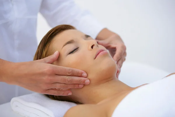 Mulher deitada de costas tem rosto massageado — Fotografia de Stock