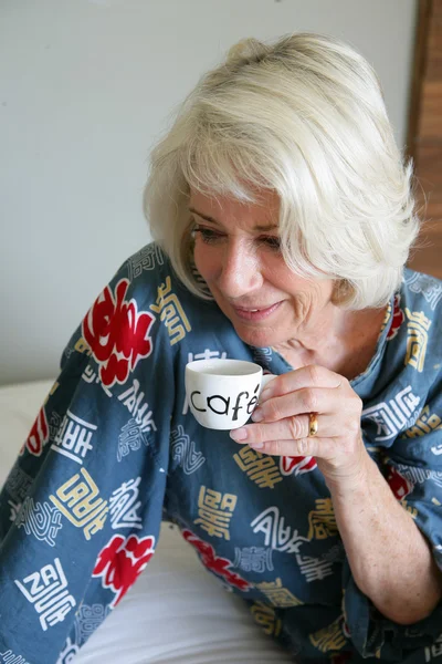 Senhora de cabelos grisalhos bebendo seu café da manhã — Fotografia de Stock