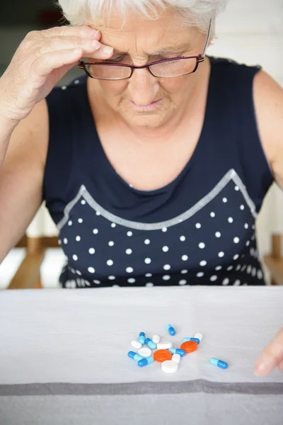 Літня жінка дивиться на свої ліки — стокове фото