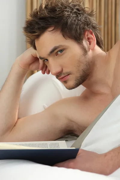 Jeune homme lisant au lit — Photo
