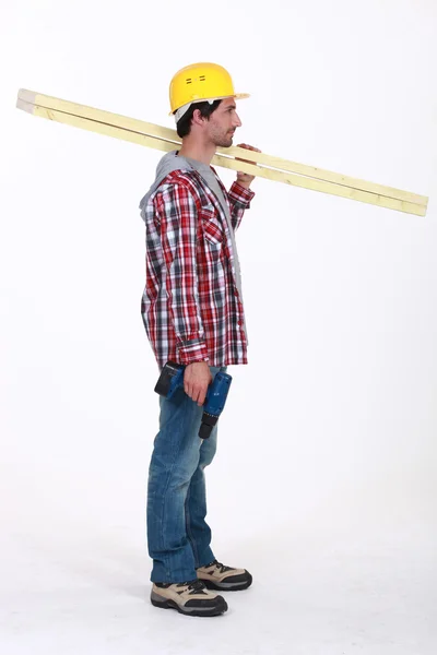 Carpinteiro em pé no perfil segurando régua sobre seu ombro — Fotografia de Stock