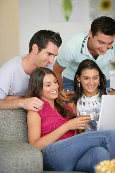 Dos parejas en casa riéndose de un portátil —  Fotos de Stock