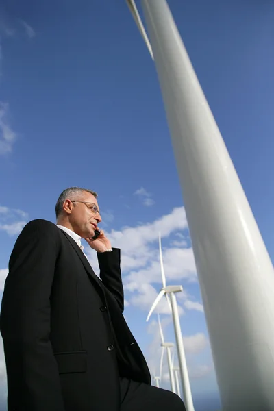 Homem com telefone celular ao lado de turbinas eólicas — Fotografia de Stock