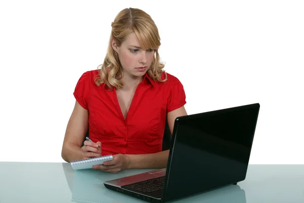 Secretária loira tomando notas da tela do laptop — Fotografia de Stock