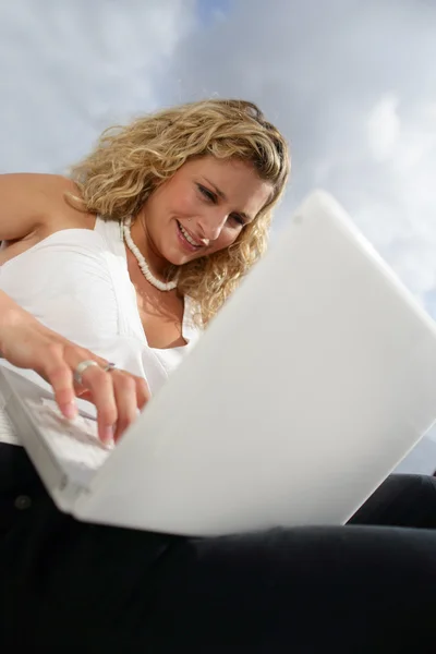 Dışarıda dizüstü bilgisayarını kullanan genç bir kadın. — Stok fotoğraf
