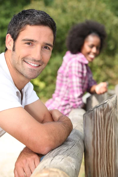 Couple leaning against a wooden barrier — Stock Photo, Image