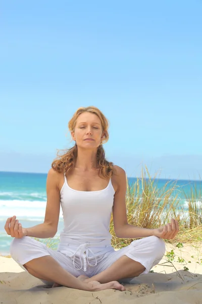 Woman meditating on a beach Stock Picture