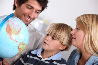 Parents and son looking at a globe clipart