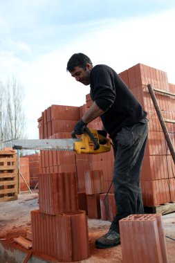 Man sawing through bricks clipart