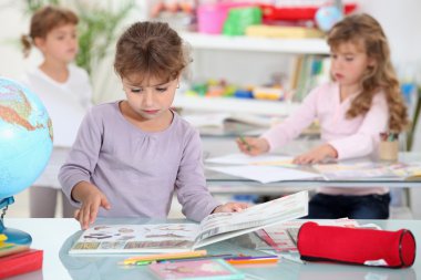 Little girls studying in a classroom clipart