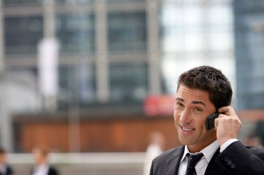 Yuppie businessman making a call outside office clipart