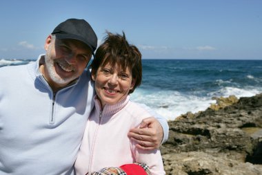 Middle-aged couple taking a walk on the beach clipart