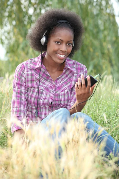 Tiener luisteren naar muziek in veld — Stockfoto