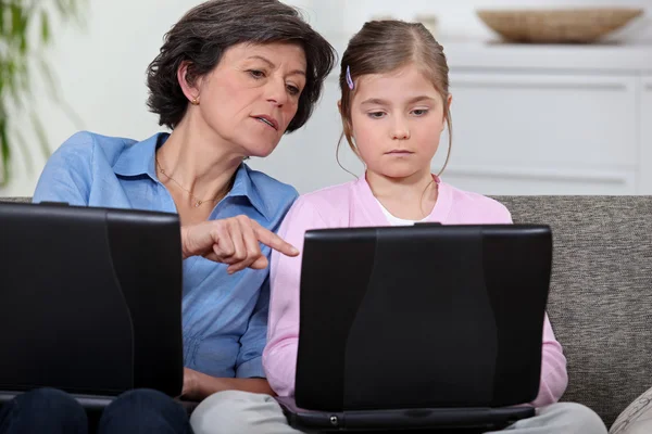 Flicka med hennes mormor och bärbara datorer — Stockfoto