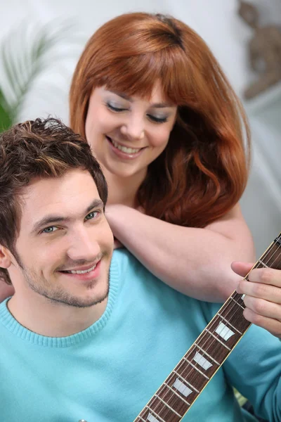 Jovem casal com uma guitarra em casa — Fotografia de Stock