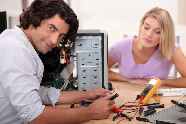Hombre de pelo medio largo está reparando una computadora frente a una mujer rubia —  Fotos de Stock