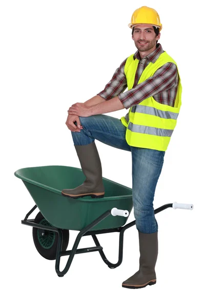 Man stood with one foot on wheelbarrow — Stock Photo, Image