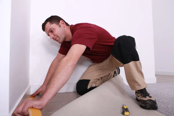 Handwerker verlegt Teppich von Wand zu Wand — Stockfoto