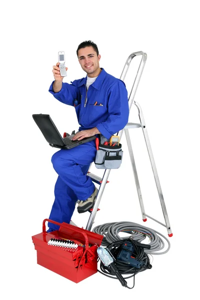 Technician with laptop and cellphone leaning on a ladder — Stock Photo, Image