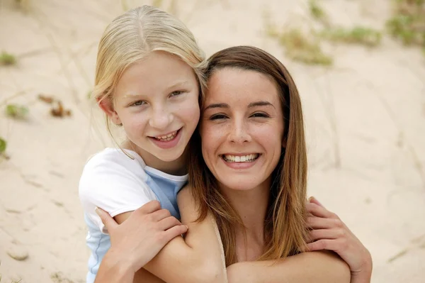 Mother and daughter sat on sand dune — Stock Photo, Image