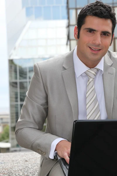 Бизнесмен, использующий ноутбук снаружи — стоковое фото