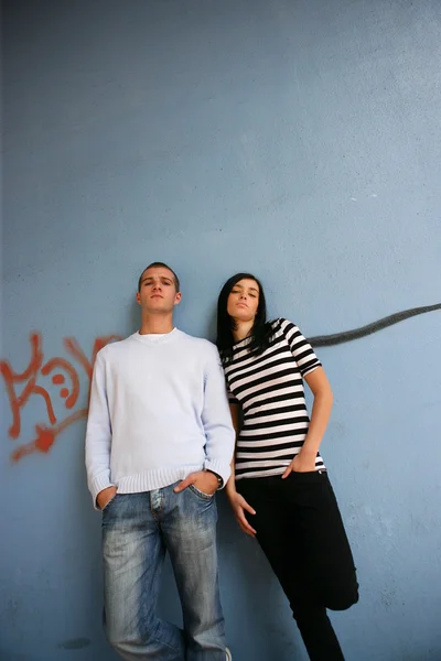 Молодой человек и молодая женщина, опирающиеся на стену — стоковое фото