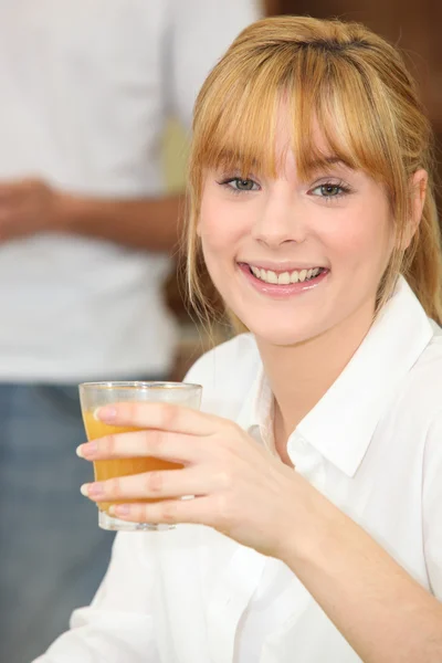 Jonge vrouw drinken van een glas sinaasappelsap — Stockfoto