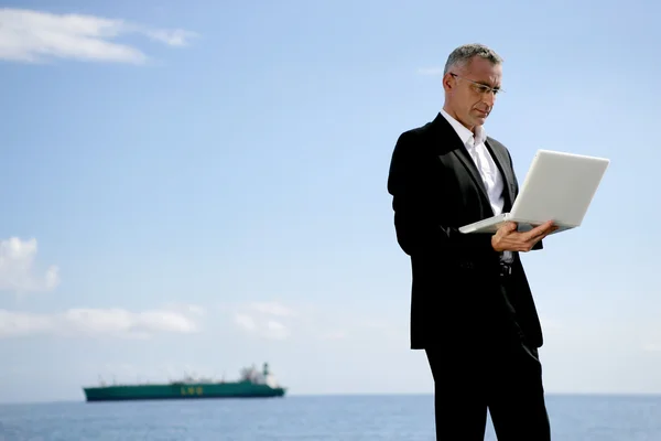 Empresário usando seu laptop na costa — Fotografia de Stock