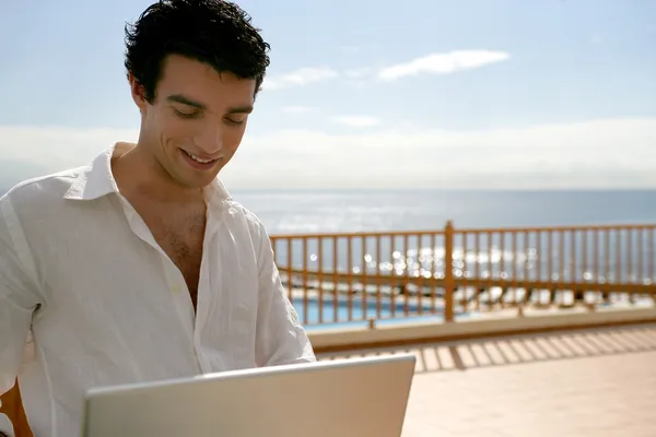 Ember használ egy laptop, a teraszon, a medence mellett — Stock Fotó