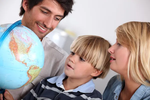 Parents et fils regardant un globe — Photo