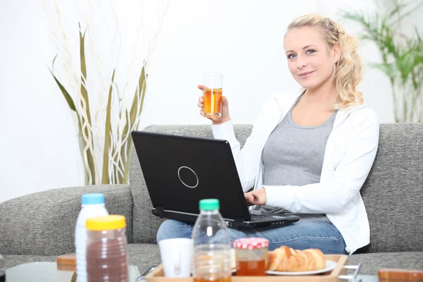 Kahvaltı zamanı bir dizüstü bilgisayar kullanan kadın — Stok fotoğraf